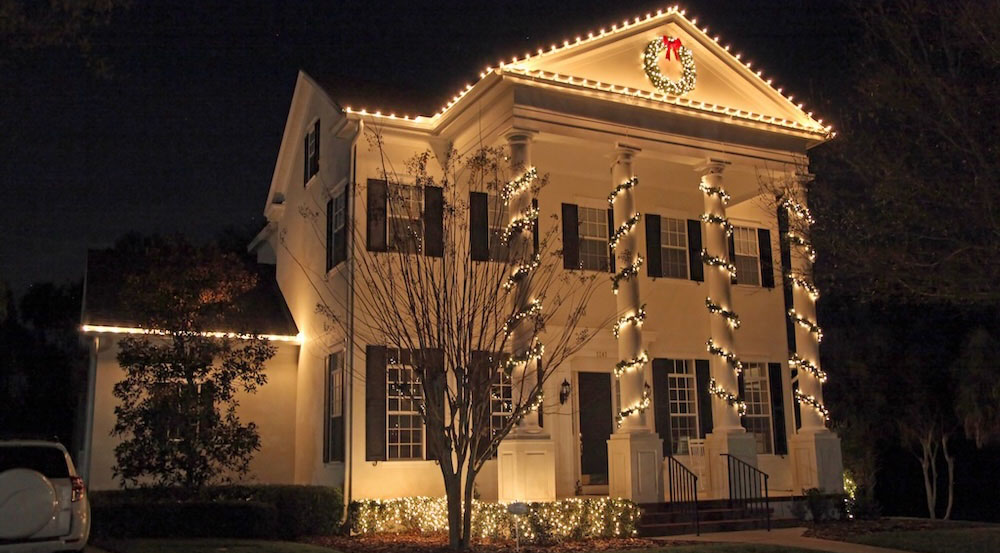 Create an inviting entrance with illuminated pillars and garland décor.